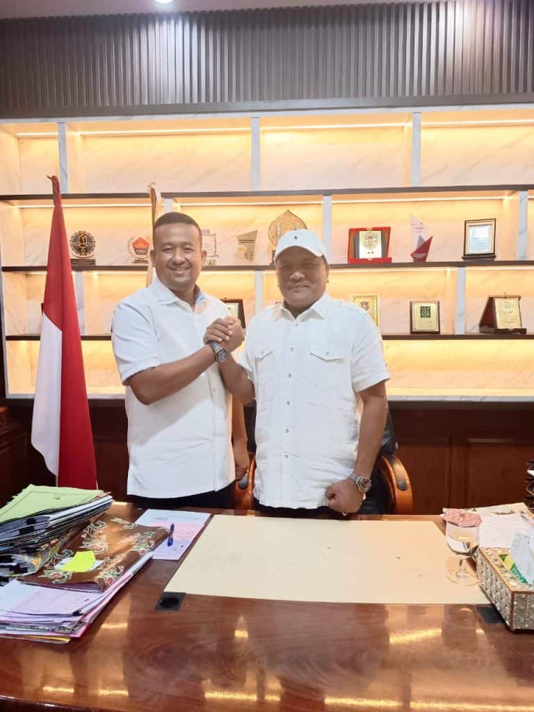 Pemerintah Aceh dan Pemkab Bireuen Perkuat Sinergi Tangani Dampak Sosial Pasca Banjir Menjabat tangan bersama di depan kantor dengan latar belakang penghargaan dan bendera Indonesia.